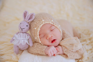Baby sleeping with a purple stuff toy