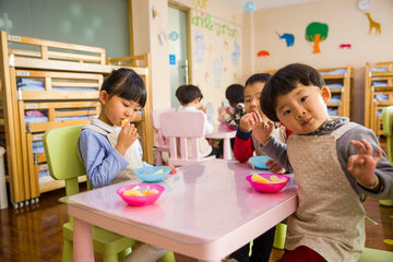 Toddler sitting on a school table eating lunch