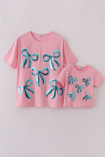 Matching pink tops with sparkly sequin bows, perfect for mom and daughter.