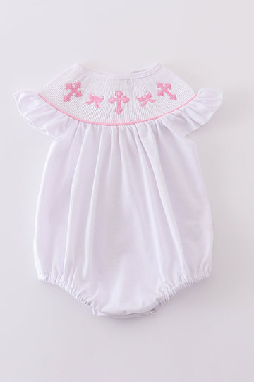 A pink smocked bubble with cross embroidery, perfect for special occasions.