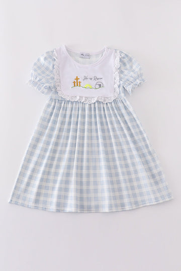A charming blue plaid dress with "He is Risen" embroidery, perfect for Easter.