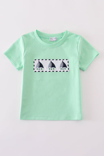 Green seersucker top with playful sailboat embroidery, perfect for summer adventures.