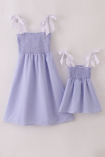 Blue stripe seersucker smocked dress with ruffled sleeves, perfect for family outings.