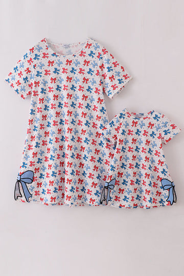 Matching mom and daughter dresses with cute bow appliques on a playful print.
