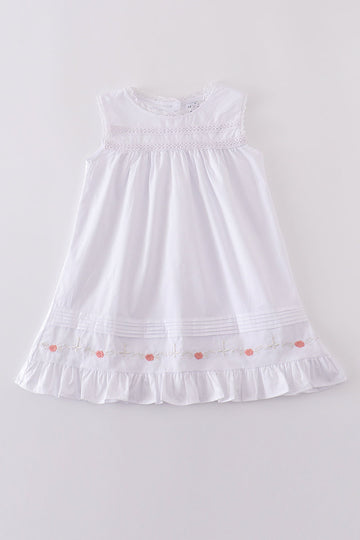 A charming white dress with floral embroidery and playful ruffle details.