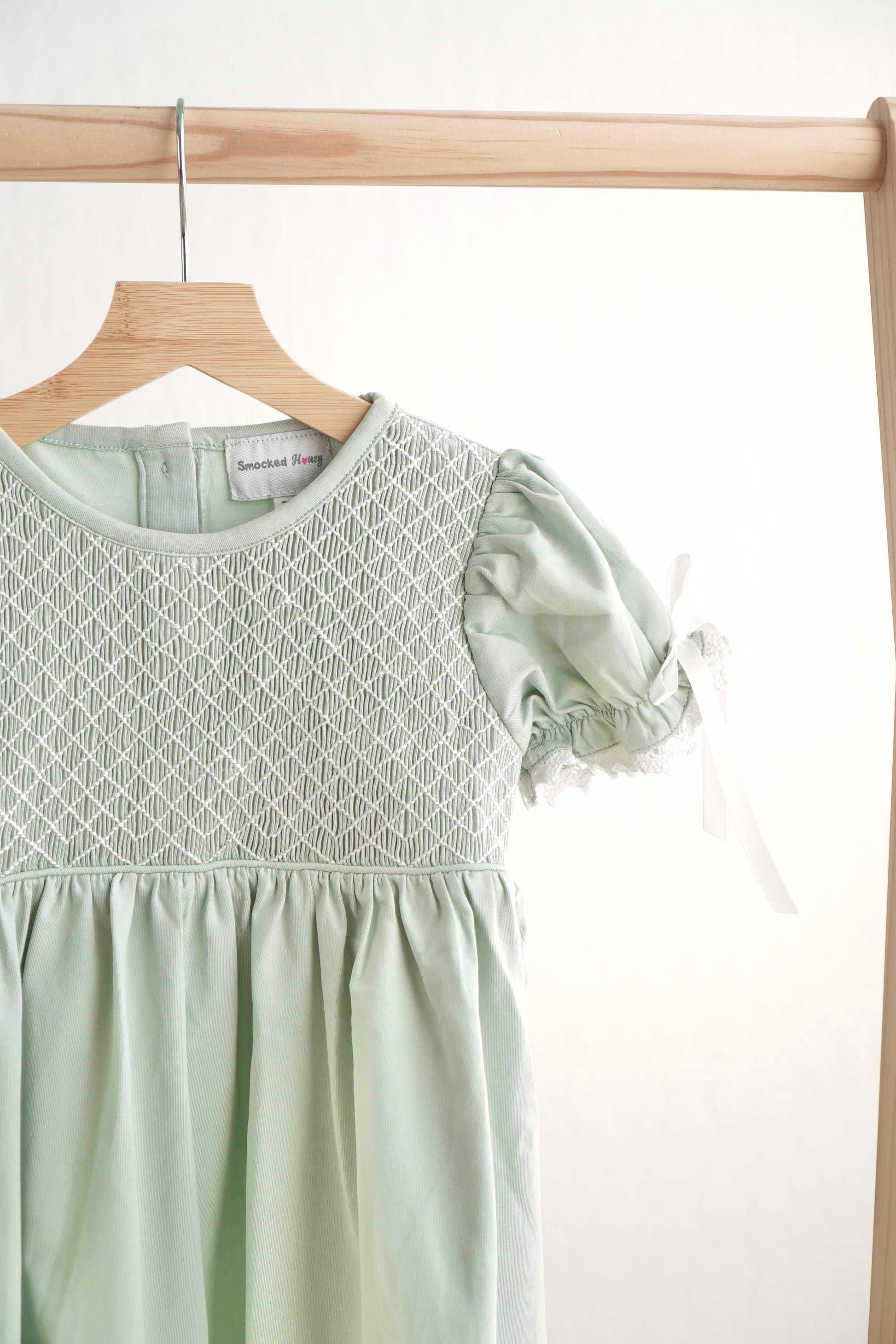 Sage green hand-smocked lace dress with puff sleeves, perfect for special occasions.