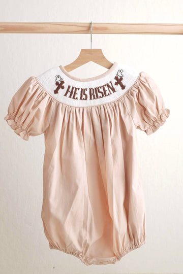 Khaki hand-smocked girl bubble with "He is Risen" embroidery, perfect for Easter.