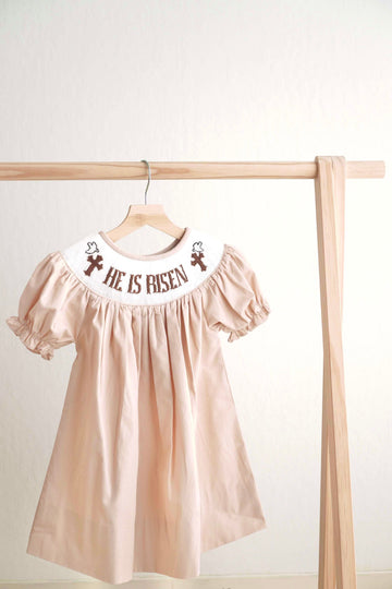 Khaki hand-smocked dress with "He is Risen" embroidery, perfect for Easter.