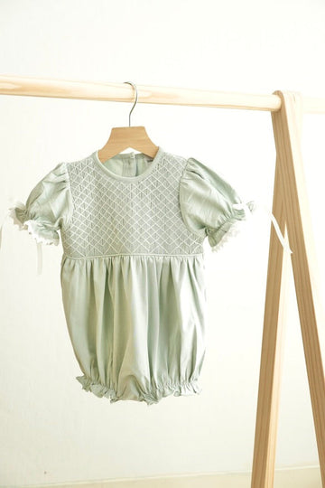 Sage green hand-smocked bubble romper with delicate lace trim for girls.