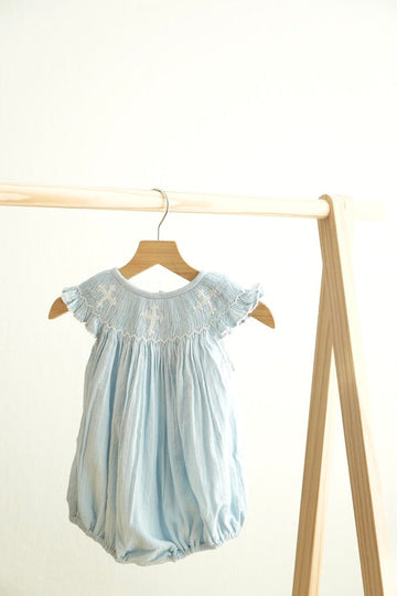 Blue Easter bubble romper with hand-smocked cross pattern, perfect for spring celebrations.