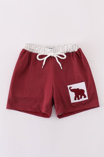 Maroon swim trunks with playful elephant embroidery, perfect for beach fun.