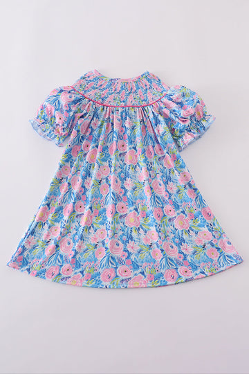 A charming blue dress with floral patterns and delicate smocking, perfect for spring.