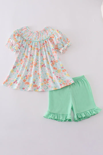 A charming green smocked dress with floral patterns, perfect for springtime adventures.