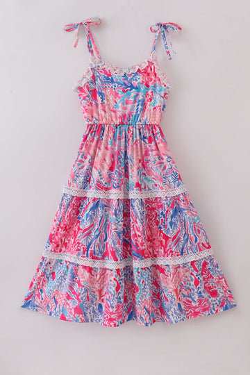 Mom wearing a vibrant tiered dress with tropical sunset wave patterns, perfect for summer.