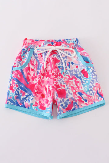 Bright swim trunks with vibrant tropical sunset and ocean wave patterns for kids.