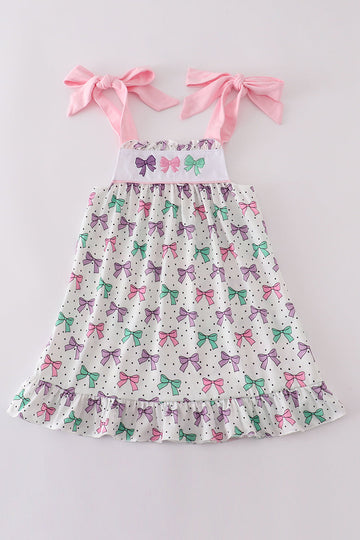 A charming pink dress with bow embroidery and playful ruffle details.