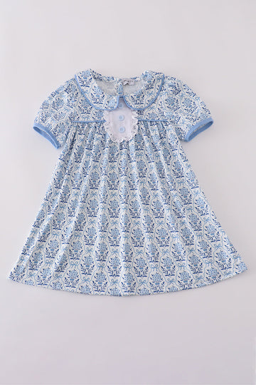 A charming blue toile garden bow dress with a playful floral pattern.