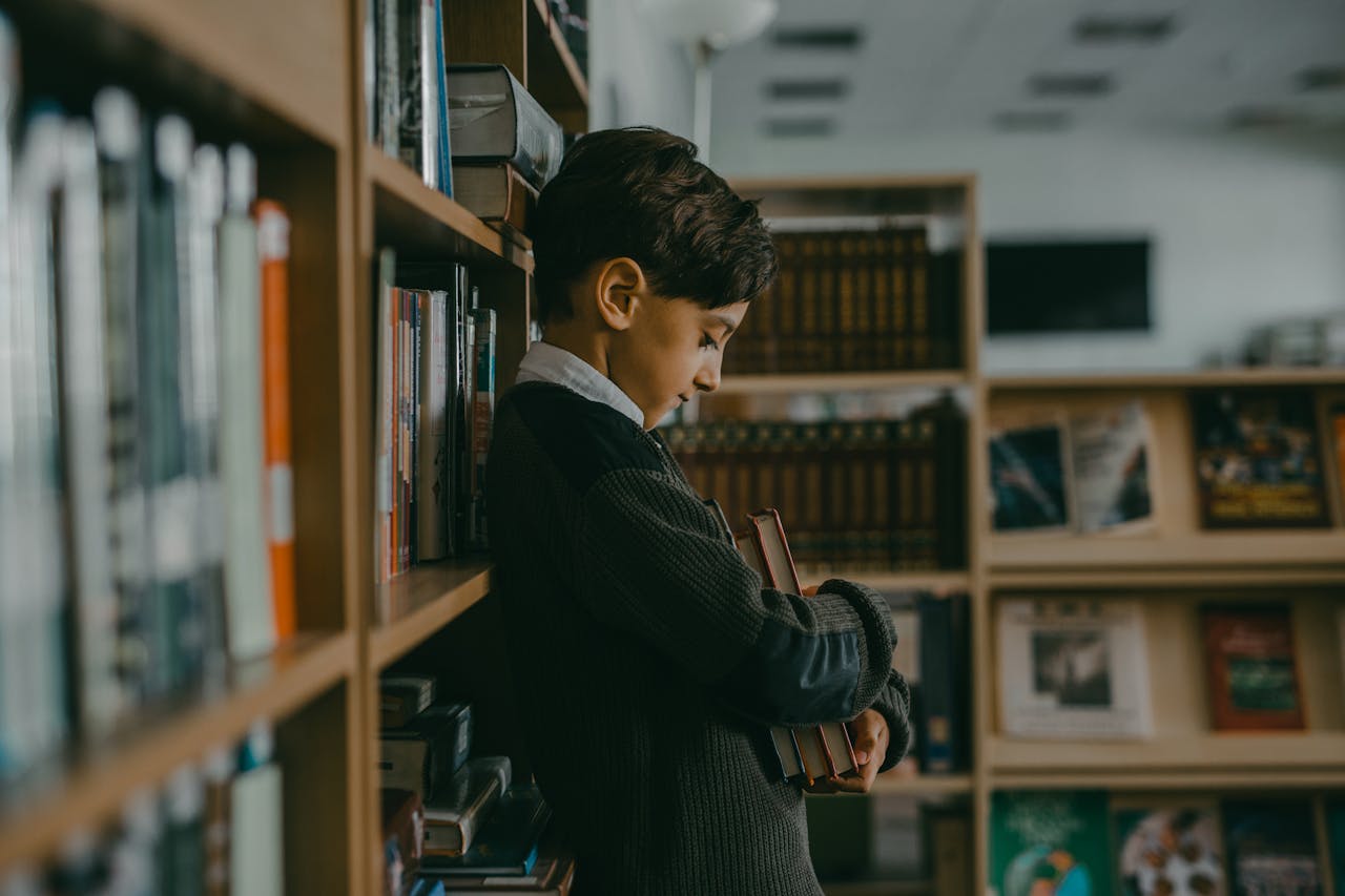 Kid leaning on a bookshelf while hugging some books