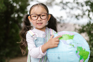 Kid wearing glasses and point towards a earth globe
