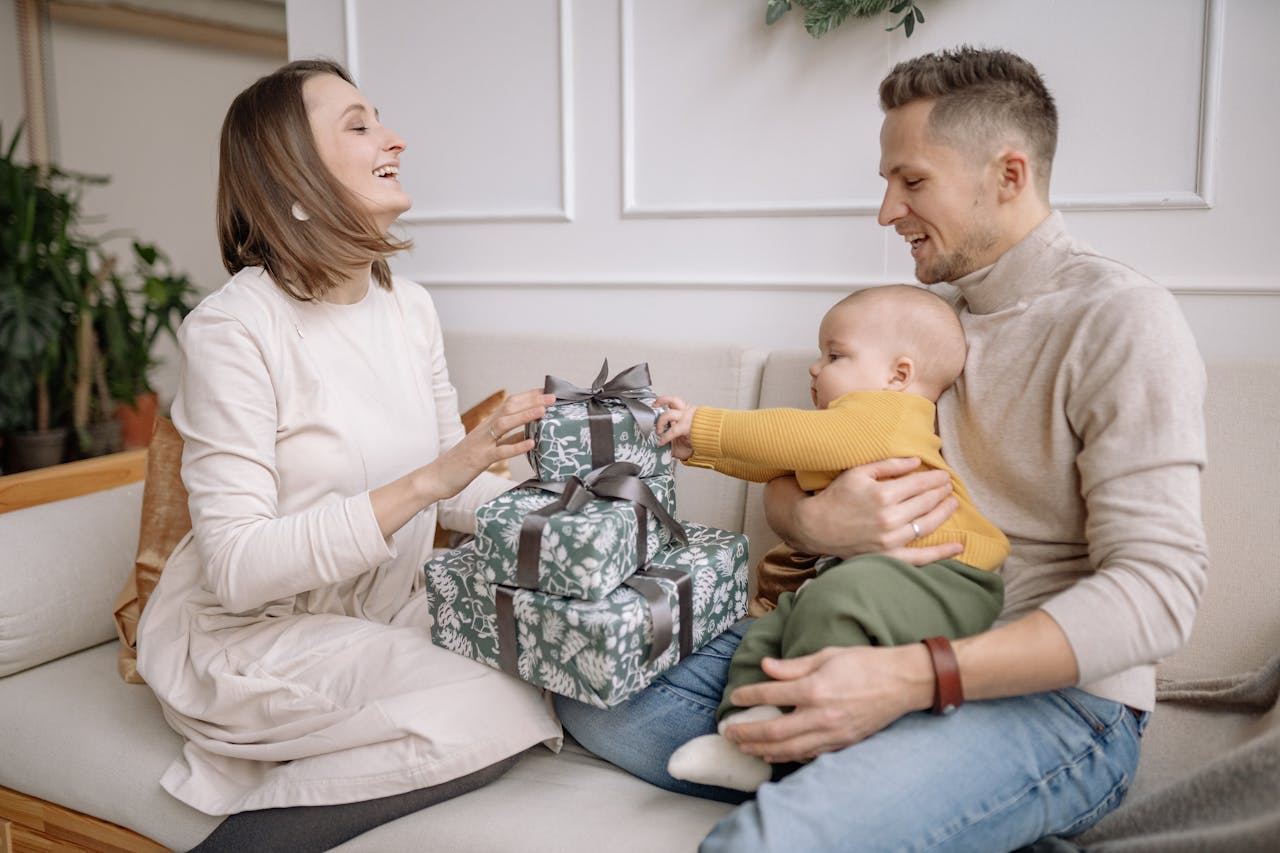 Parents opening gifts with baby in their lap