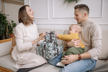 Parents opening gifts with baby in their lap