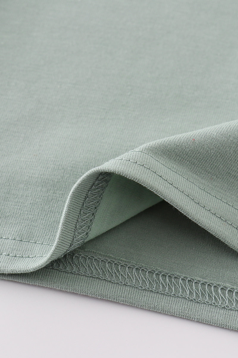 Sage green boy's shirt with delicate sand dollar embroidery, perfect for beach outings.
