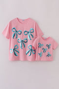Matching pink tops with sparkly sequin bows, perfect for mom and daughter.