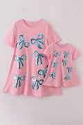Matching pink sequin dresses with big bows, perfect for mom and daughter.