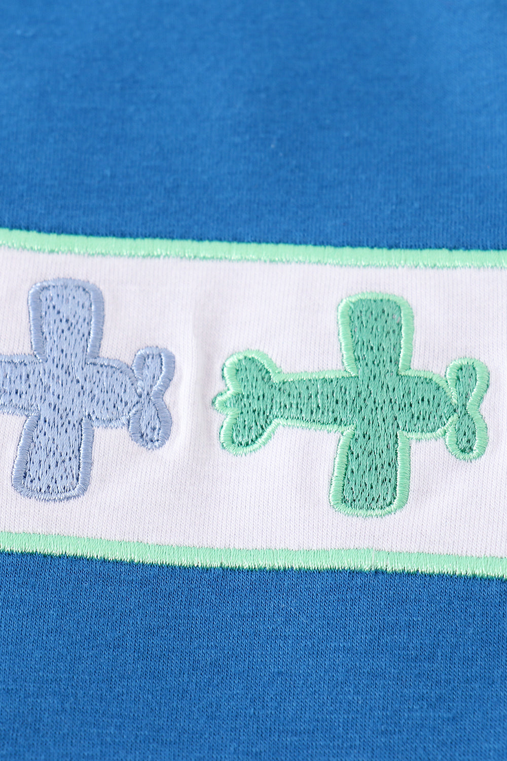 Blue top with playful airplane embroidery, perfect for kids' adventures.