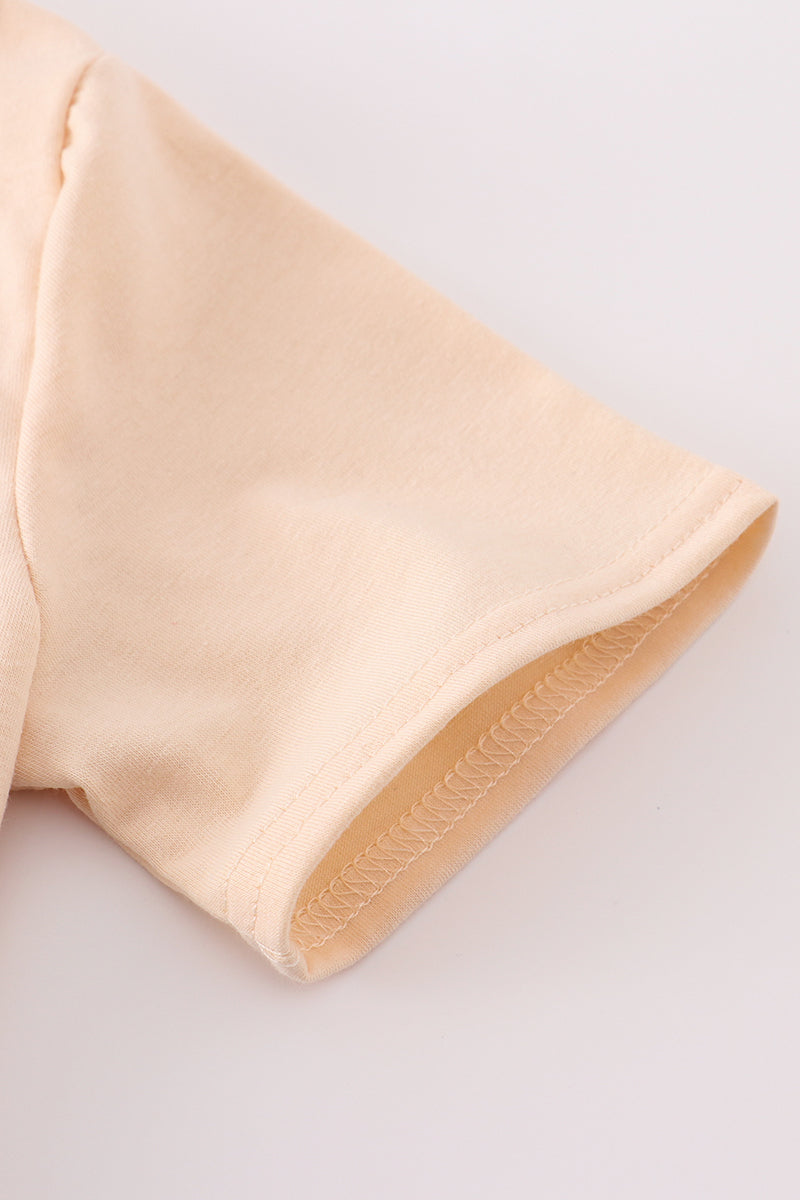 Cream top with delicate cross-stitch knots, perfect for everyday play.