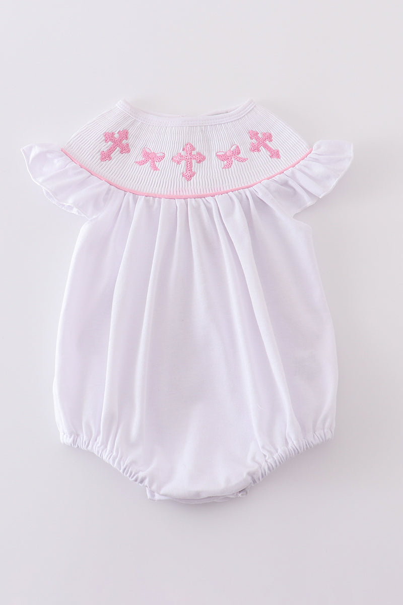 A pink smocked bubble with cross embroidery, perfect for special occasions.