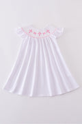 A charming pink dress with cross embroidery and smocked detailing, perfect for playdates.