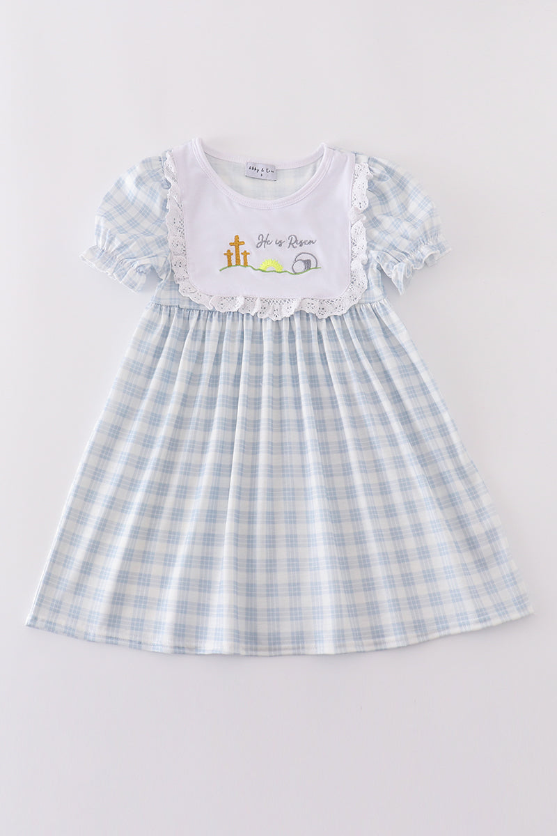 A charming blue plaid dress with "He is Risen" embroidery, perfect for Easter.
