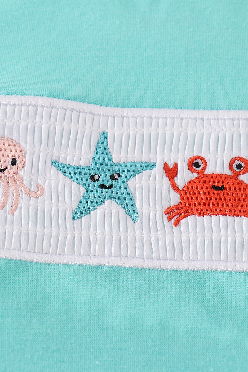Adorable blue bubble romper with marine creature embroidery and smocked detailing.