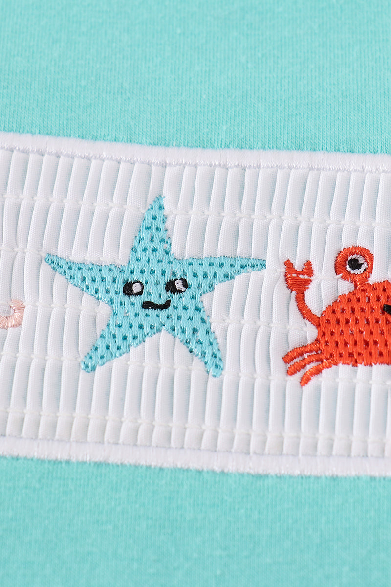 Children's blue smocked top with cute marine creature embroidery.
