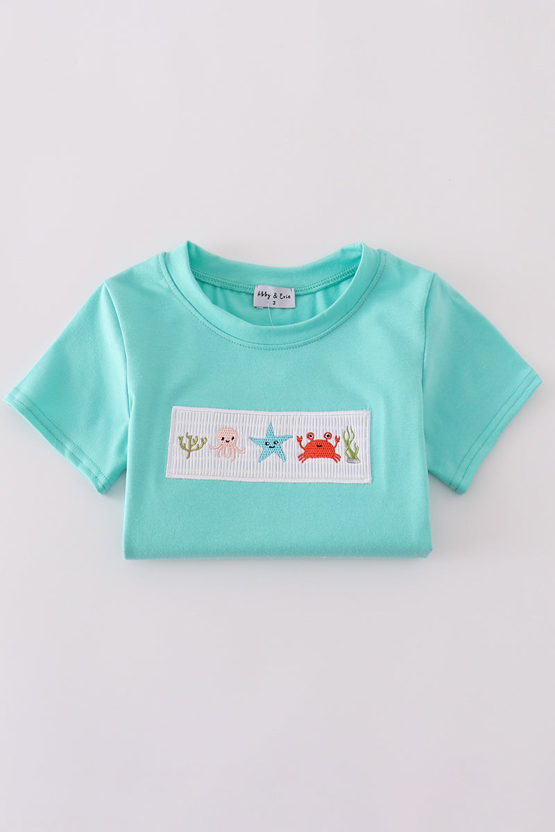Children's blue smocked top with cute marine creature embroidery.