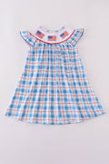 A charming smocked dress with colorful flag embroidery, perfect for festive occasions.