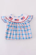 A charming smocked dress with colorful flag embroidery, perfect for festive occasions.
