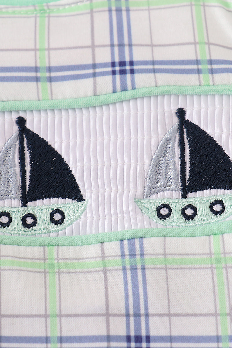A charming green seersucker bubble with sailboat embroidery, perfect for summer fun.
