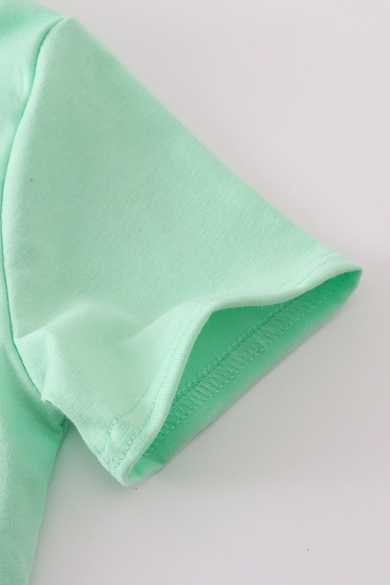 Green seersucker top with playful sailboat embroidery, perfect for summer adventures.