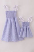 Blue stripe seersucker smocked dress with ruffled sleeves, perfect for family outings.