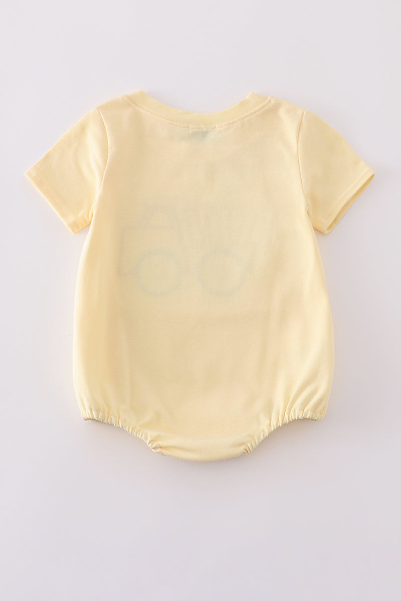 Bright yellow bubble romper with a playful truck applique, perfect for toddlers.