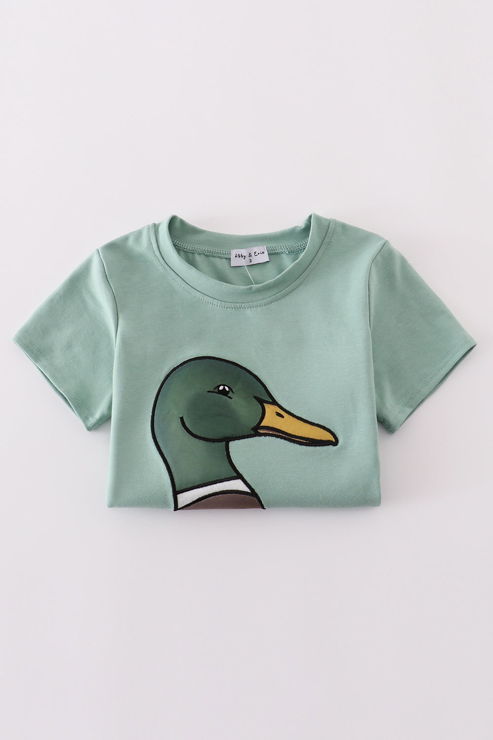 Green top with playful duck applique, perfect for kids' everyday adventures.