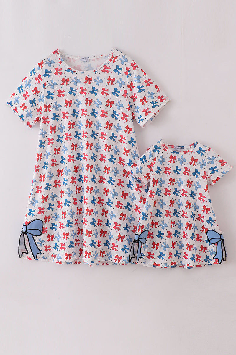 Matching mom and daughter dresses with cute bow appliques on a playful print.
