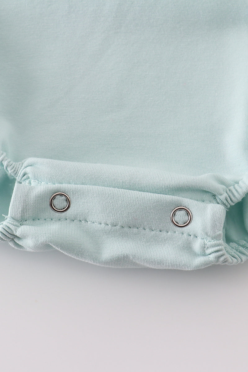 A charming blue bubble romper with pearl smocking and a cute bow accent.