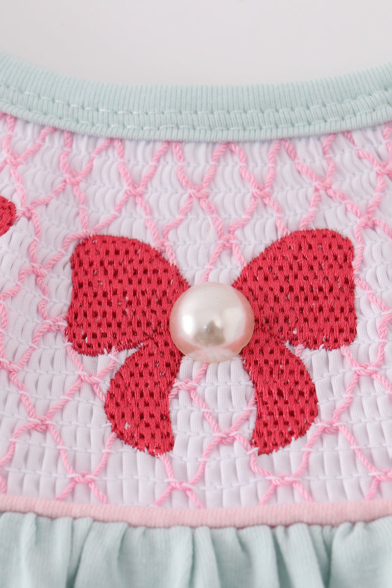 A charming blue bubble romper with pearl smocking and a cute bow accent.