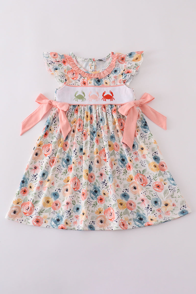 A charming dress with floral crab embroidery, bow, and playful ruffles.