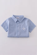 A charming blue button-down shirt with cross embroidery, perfect for kids.