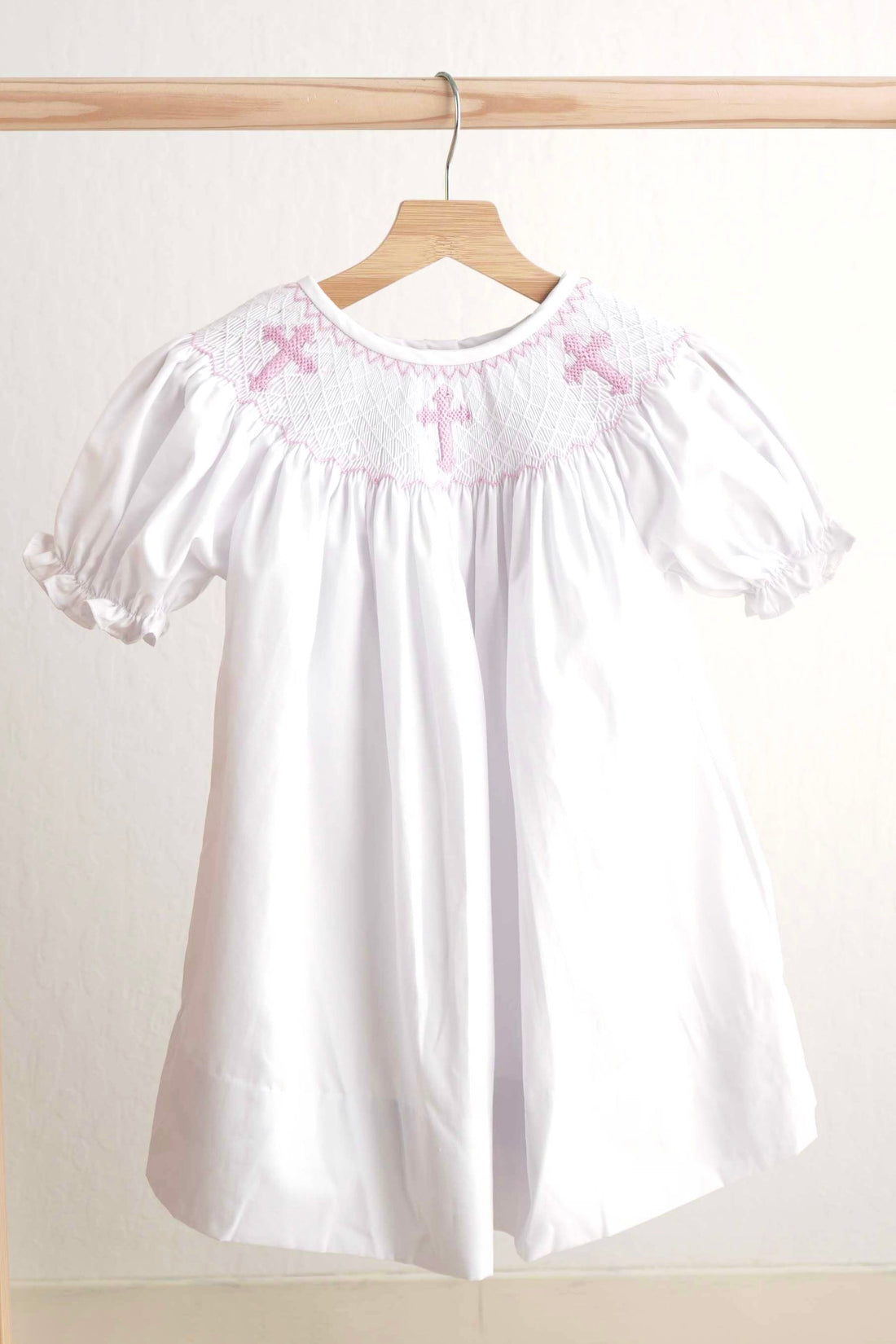 Pink Easter dress with hand-smocked cross pattern, perfect for spring celebrations.