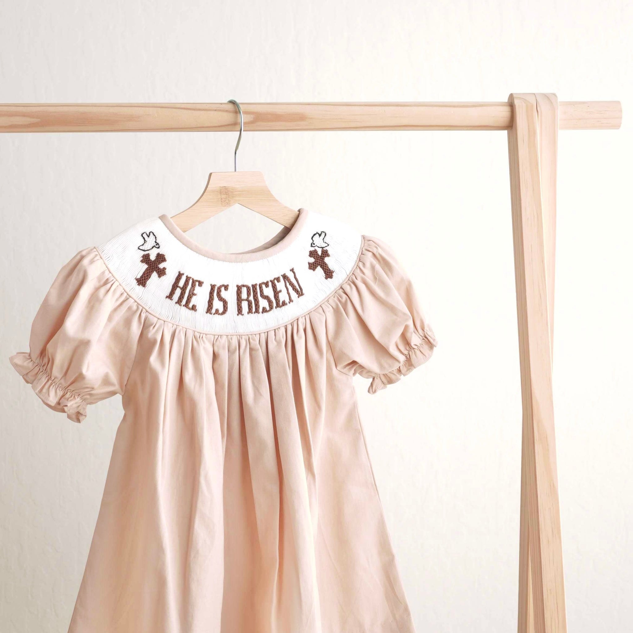 Khaki hand-smocked dress with "He is Risen" embroidery, perfect for Easter.